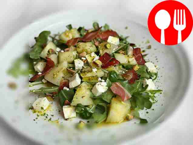 Delicious salad with melon, feta, crispy bacon and pistachios