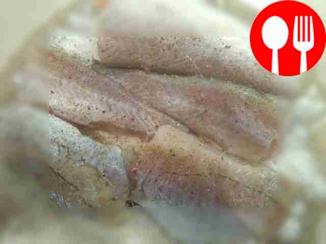 Cut the washed and cleaned fish in half along...