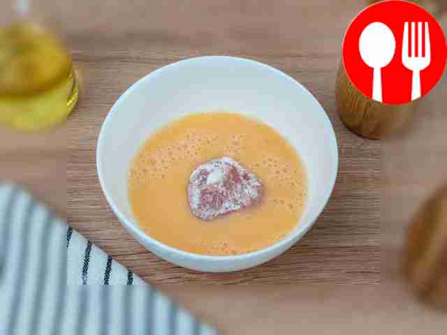 Dip a piece of chicken into the beaten egg.