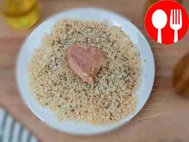 Coat a piece of chicken in breadcrumbs.